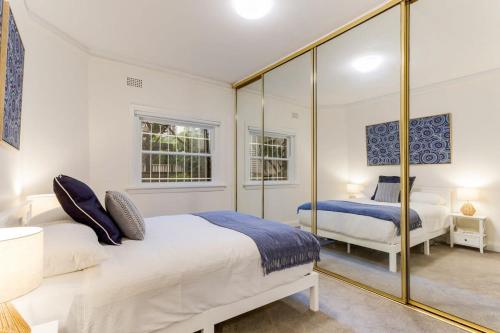 a bedroom with two beds and a large mirror at Art Deco Apartment Meters Away From The Beach in Sydney
