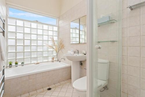 a bathroom with a sink and a tub and a toilet at Clovelly Beach House - Sea, Sand and Exclusivity in Sydney