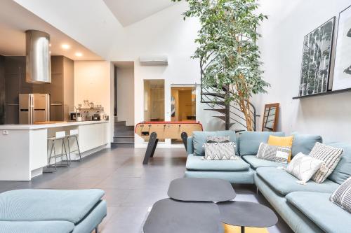 un salon avec des canapés bleus et une cuisine dans l'établissement NOCNOC Loft L'atypique - 185m2 Centre de Nantes, à Nantes