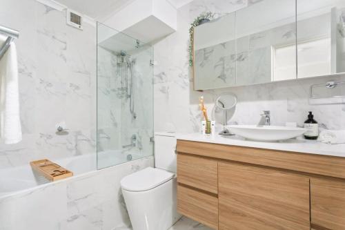 e bagno con servizi igienici, lavandino e doccia. di Elegant 2-Bed Unit with Expansive Harbour Views a Sydney