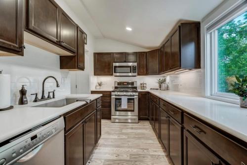 a kitchen with wooden cabinets and a large window at Del Norte Cottage - Downtown King BBQ Fire Pit in Colorado Springs