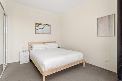 um quarto branco com uma cama e uma fotografia na parede em Charming 1-Bed Apartment Close to Shops and Parks em Sydney