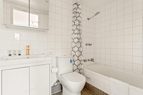 a bathroom with a toilet and a tub and a sink at Charming 1-Bed Apartment Close to Shops and Parks in Sydney