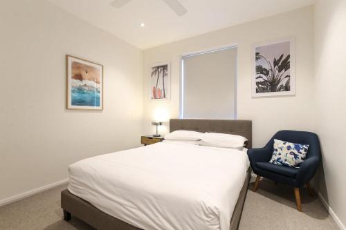 a bedroom with a bed and a blue chair at Gorgeous 2-Bed Apartment By Shops and the River in Batemans Bay