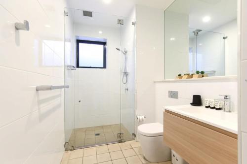 a white bathroom with a shower and a toilet at Gorgeous 2-Bed Apartment By Shops and the River in Batemans Bay