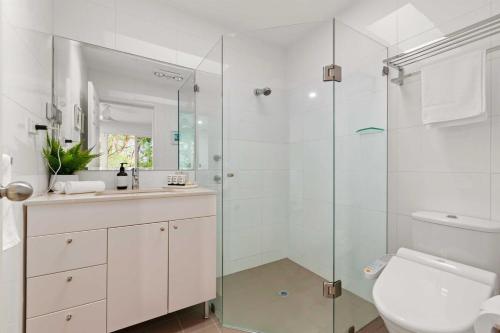 a bathroom with a toilet and a glass shower at Leafy Retreat with Deck & City Convenience in Sydney