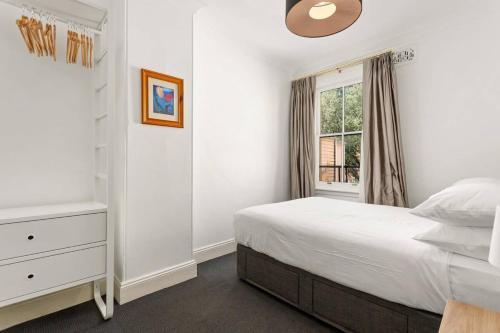 a white bedroom with a bed and a window at Traditional 2-Bed Terrace House in Millers Point in Sydney