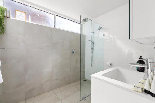 een badkamer met een glazen douche en een wastafel bij Beautiful Boho 3-Bed by the Beach & the Bush in Sydney