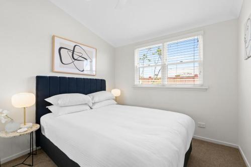 a bedroom with a large white bed and a window at Chic 2-Bed Unit Fully Renovated in Prime Location in Sydney