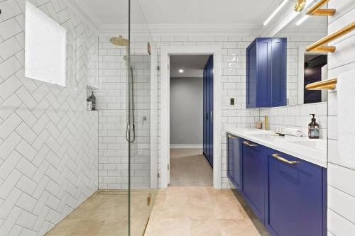 a bathroom with blue cabinets and a glass shower at Impeccably Chic 4-Bed Home with Spa & Pool in Sydney