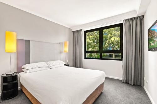 1 dormitorio con cama grande y ventana grande en Sleek 1-Bed by Jubilee Park with Rooftop Pool, en Sídney