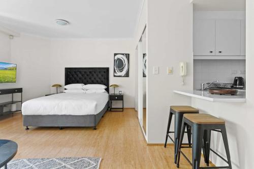 1 dormitorio con 1 cama y cocina con taburetes en Idyllic Studio by University Campuses, en Sídney