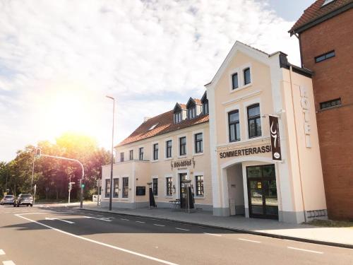 a white building on the corner of a street at Hotel Kolossos Düsseldorf - Neuss in Neuss