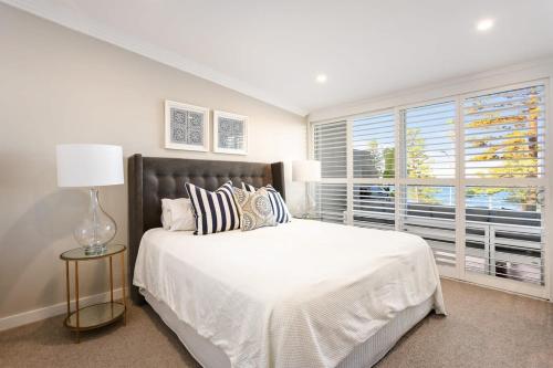 a bedroom with a large white bed and a window at Glorious Beachfront 3-Bed with Breathtaking Views in Deewhy