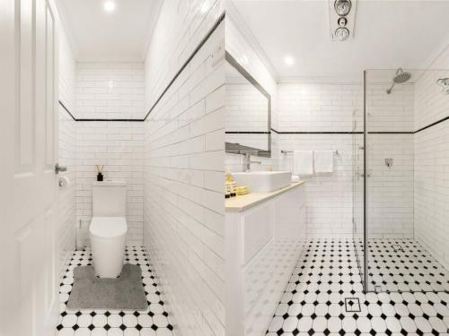 a white bathroom with a toilet and a sink at Quaint 3-Bed Heritage Home in the Heart of Sydney in Sydney