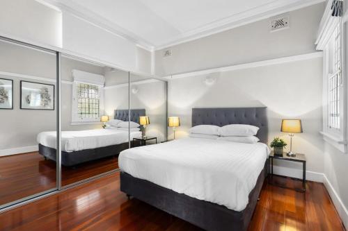 a bedroom with two beds and two lamps and mirrors at Huge Harbour View Apartment In Historic Home in Sydney