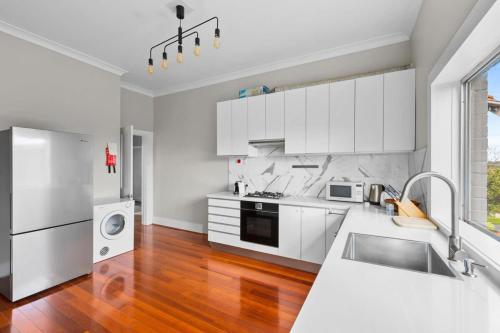 a kitchen with white cabinets and a wooden floor at Huge Harbour View Apartment In Historic Home in Sydney