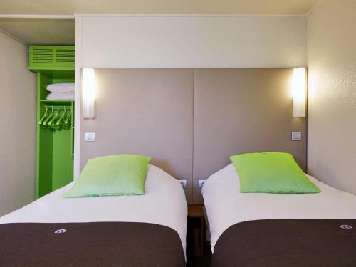 2 Betten in einem Zimmer mit grünen Kissen in der Unterkunft Hotel Campanile Besançon Nord Ecole Valentin in Besançon