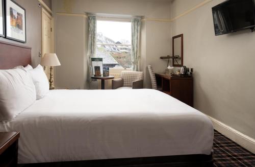 a hotel room with a large white bed and a window at The Ambleside Inn - The Inn Collection Group in Ambleside