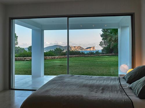 Villa Alexia - San Jose في Sant Francesc de s'Estany: غرفة نوم مع نافذة زجاجية كبيرة مطلة
