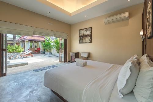 a bedroom with a large white bed and a patio at Villa Sri Suri in Rawai Beach