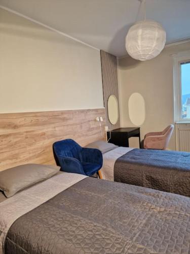 um quarto de hotel com duas camas e uma cadeira azul em Premium Avkoppling Tre Rum av Perfektion em Gotemburgo