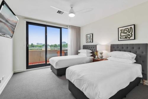 a hotel room with two beds and a large window at Spacious 3-Bed Apartment by the MCG in Melbourne