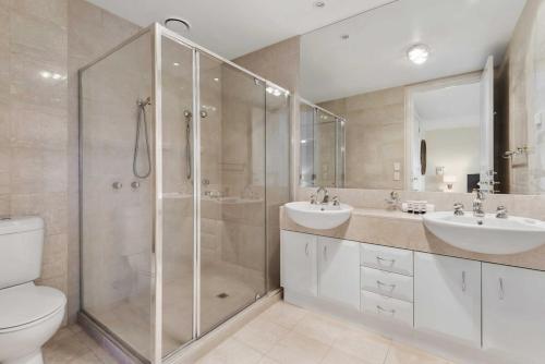 a bathroom with a shower and two sinks and a toilet at Spacious 3-Bed Apartment by the MCG in Melbourne