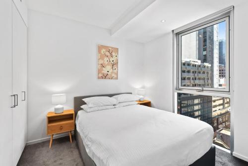 Habitación blanca con cama y ventana en Sleek 2-Bed Apartment with Beautiful City Views, en Melbourne