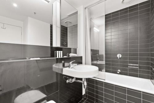 Baño en blanco y negro con lavabo y espejo en Sleek 2-Bed Apartment with Beautiful City Views, en Melbourne