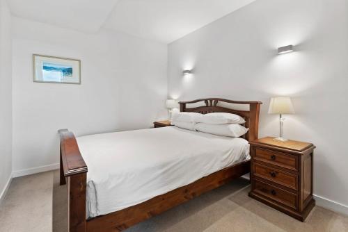 a bedroom with a wooden bed and a nightstand with a lamp at Beautiful 1-Bed Unit in The Heart of Melbourne in Melbourne