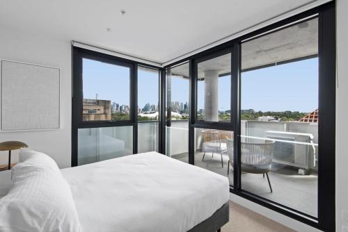 a bedroom with a white bed and a balcony at Executive 2-Bed Apartment with Views, Gym and Pool in Melbourne