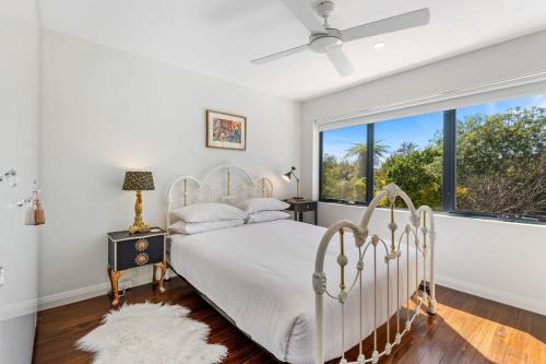 a bedroom with a white bed and a large window at Delightful 2-Bed Townhouse Close to the Beach in Frankston