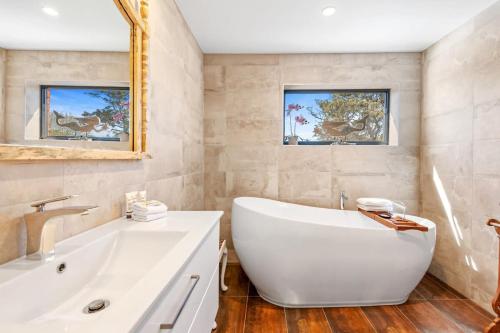 a bathroom with a large white tub and a sink at Delightful 2-Bed Townhouse Close to the Beach in Frankston