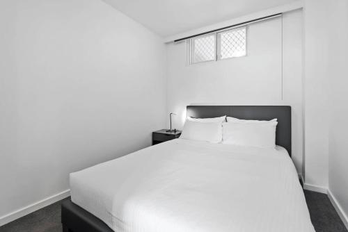 a white bedroom with a white bed and a window at Contemporary 1-Bed Apartment Moments from MCG DUPLICATE in Melbourne