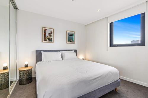 Un dormitorio blanco con una cama grande y una ventana en Pristine 2-Bed Unit With Beautiful City Landscape en Melbourne