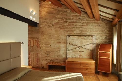 a bedroom with a brick wall and a bed at Locanda Ponte Dante in Treviso