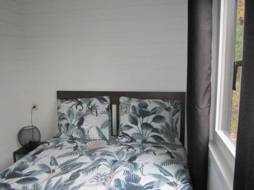 a bedroom with a bed with blue and white sheets at Le Petit Chalet in Resteigne