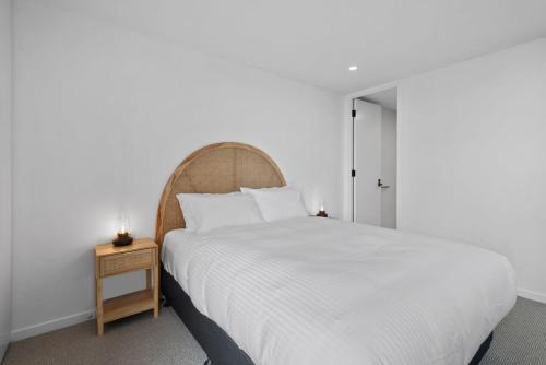 1 dormitorio con 1 cama blanca grande y mesita de noche en Bespoke 2-Bed Beachfront Apartment, en Melbourne
