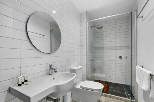a bathroom with a sink and a toilet and a mirror at Vibrant 2-Bed Apartment Near St Kilda Beach in Melbourne