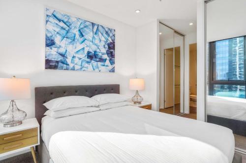 Un dormitorio con una cama blanca y una pintura en la pared en Southbank Central 2-Bed - Pool, Gym & City Views, en Melbourne