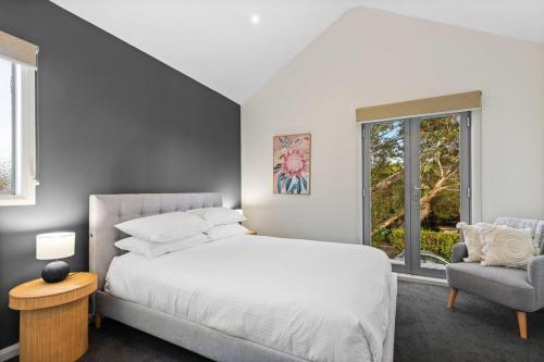 Un dormitorio con una cama blanca y una silla. en Chic 2-Bed Home By Bustling Shops, en Yarraville