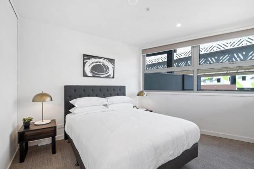 biała sypialnia z dużym łóżkiem i oknem w obiekcie Elegant 2-Bed with Large Balcony by High Street w Melbourne