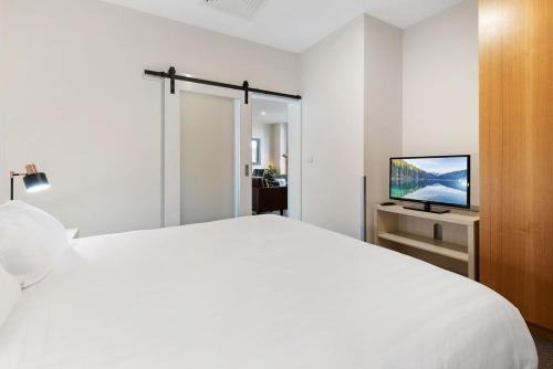 Habitación blanca con cama y TV en Unbeatable 2-Bed Apartment In City Centre en Melbourne