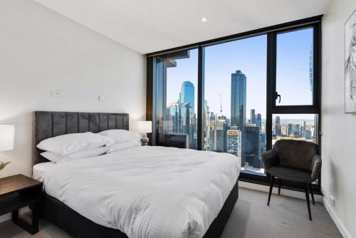 a bedroom with a large bed and a large window at Chic Central Pad with City Views, Pool and Gym in Melbourne