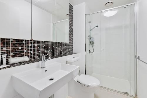 a bathroom with a sink and a toilet and a shower at Chic Central Pad with City Views, Pool and Gym in Melbourne