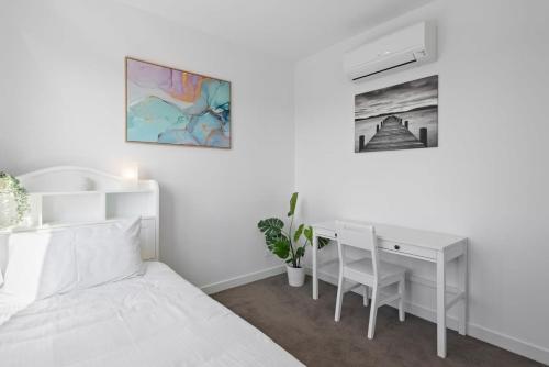 a white bedroom with a desk and a bed at Stylish and Convenient Two Bedroom Apartment in Burwood