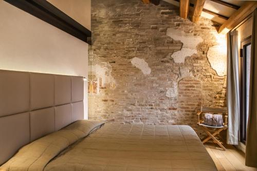 a bed in a room with a brick wall at Locanda Ponte Dante in Treviso
