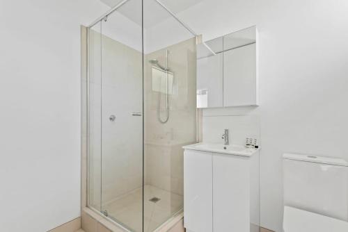ein weißes Bad mit einer Dusche und einem Waschbecken in der Unterkunft Polished 1-Bed St Kilda Pad in Prime Location in Melbourne
