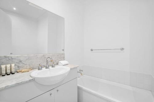 3-Bed Waterfront Family Home in Scenic Location في Patterson Lakes: حمام أبيض مع حوض وحوض استحمام